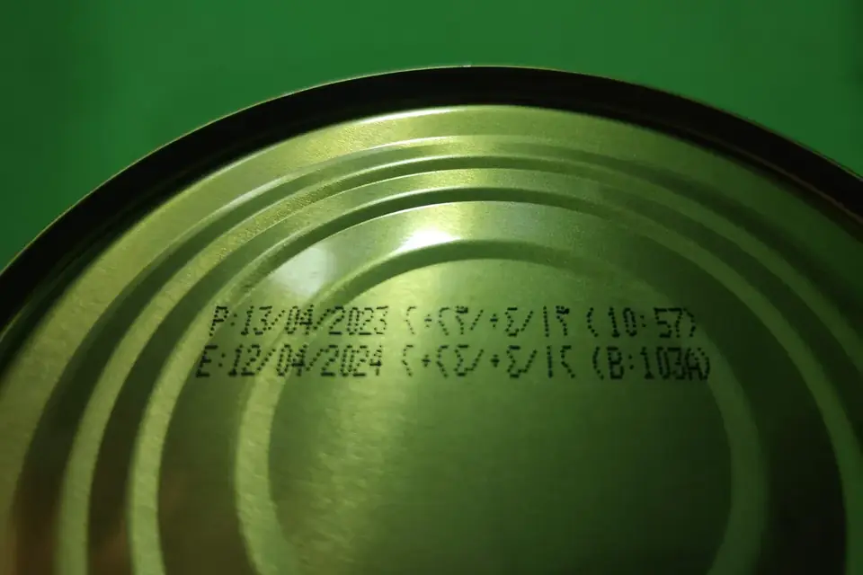 Gros plan sur le fond d'une boîte de conserve où sont imprimées une date de fabrication et une date limite