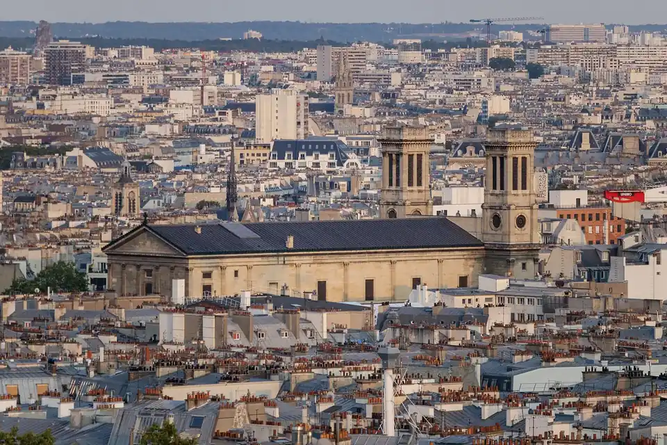 Vue plongeante sur les toits en zinc et les immeubles de Paris, avec une église à colonnes au centre